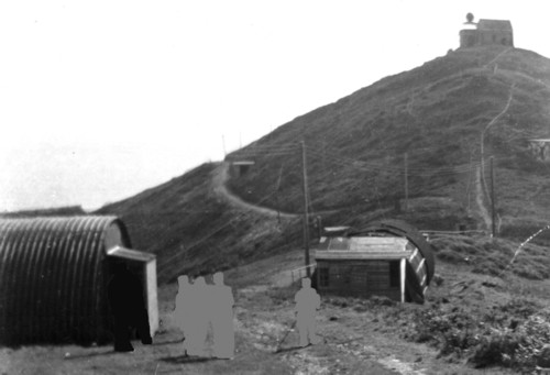 Wartime photo of station in background and Nissen huts in foreground
